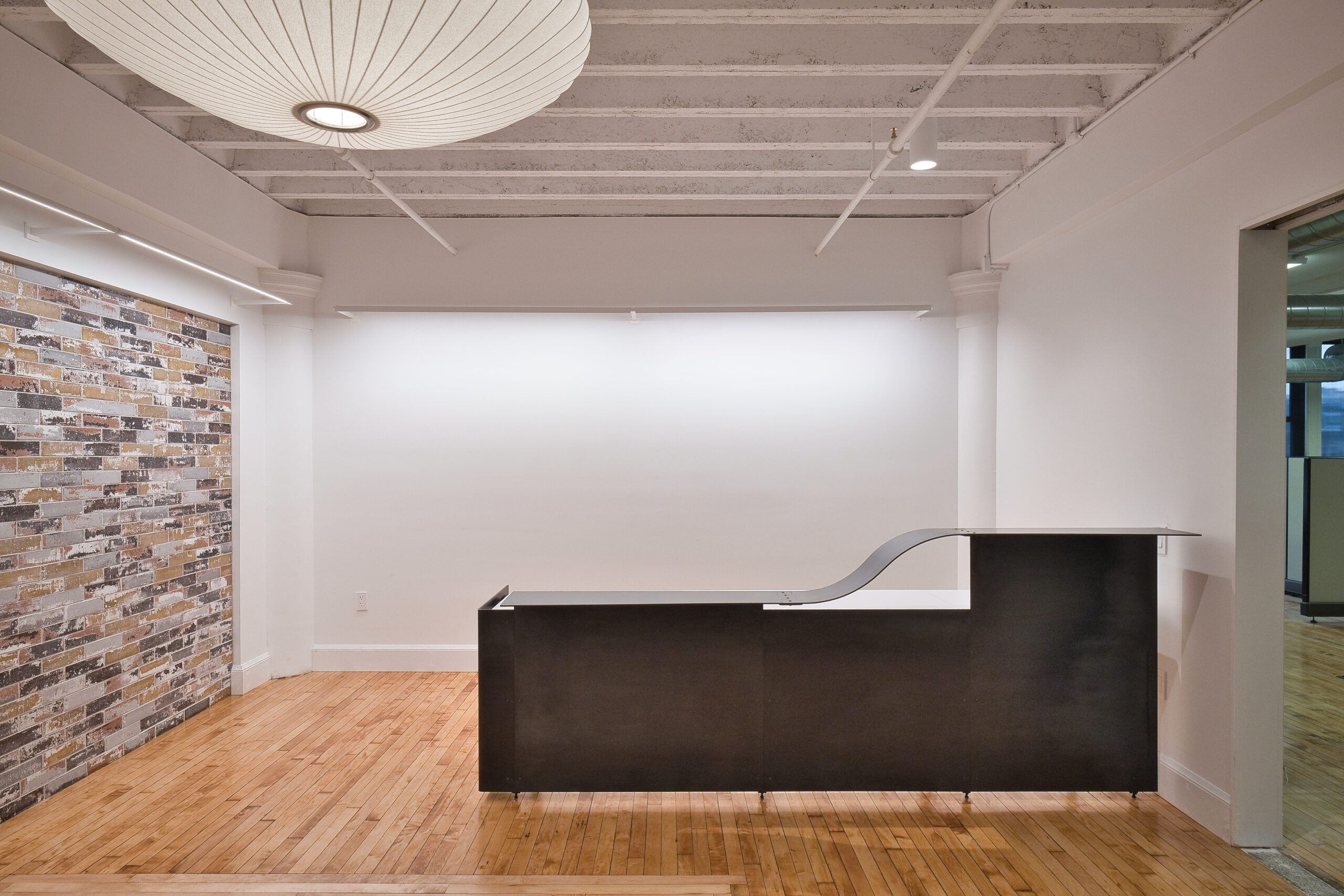 Photograph of the renovated reception space showing custom reception desk and brick tile feature wall.