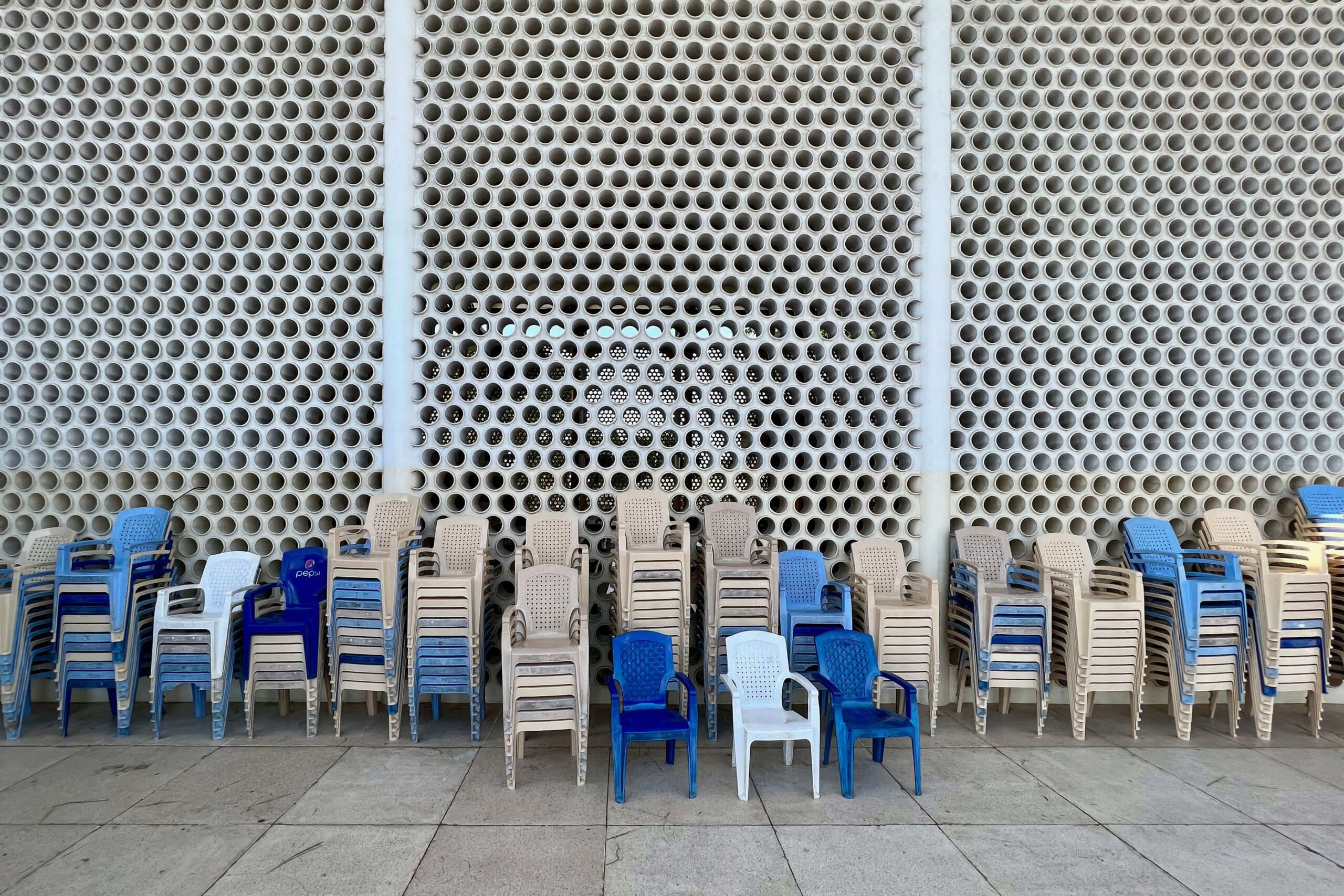 Perforated sanctuary facade with stacked plastic chairs