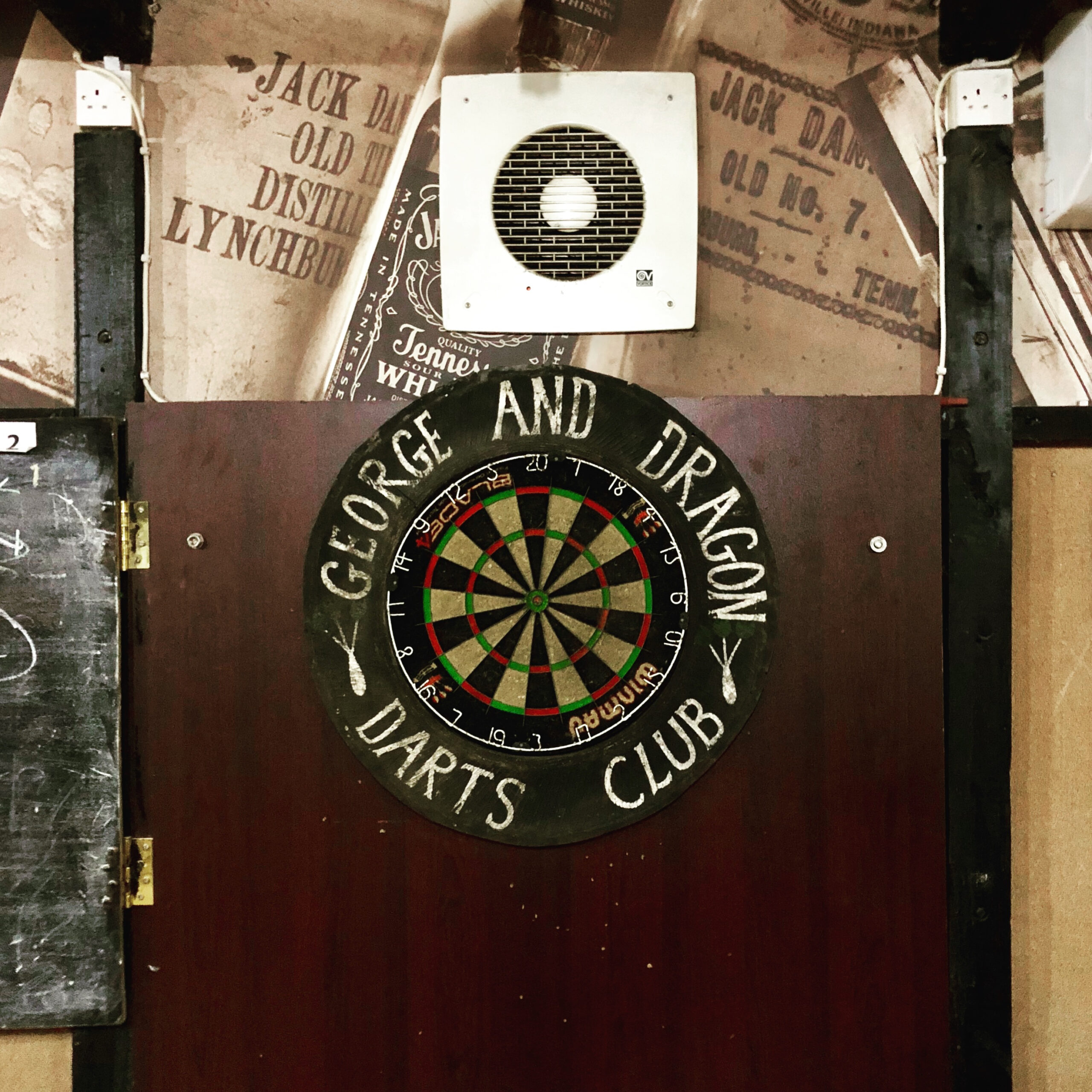 Interior view of George and Dragon with dartboard and exhaust fan